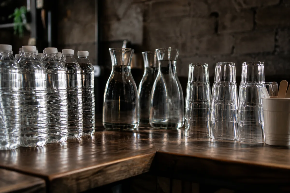 Comptoir de buvette associative avec bouteilles d&rsquo;eau, carafes et gobelets réutilisables